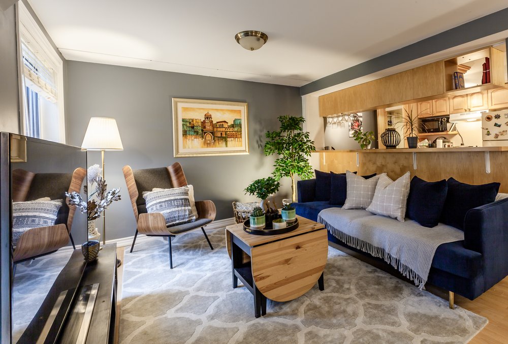Living room designed and furnished by Build a BnB, featuring a navy velvet sofa, wing chairs, and gallery wall art